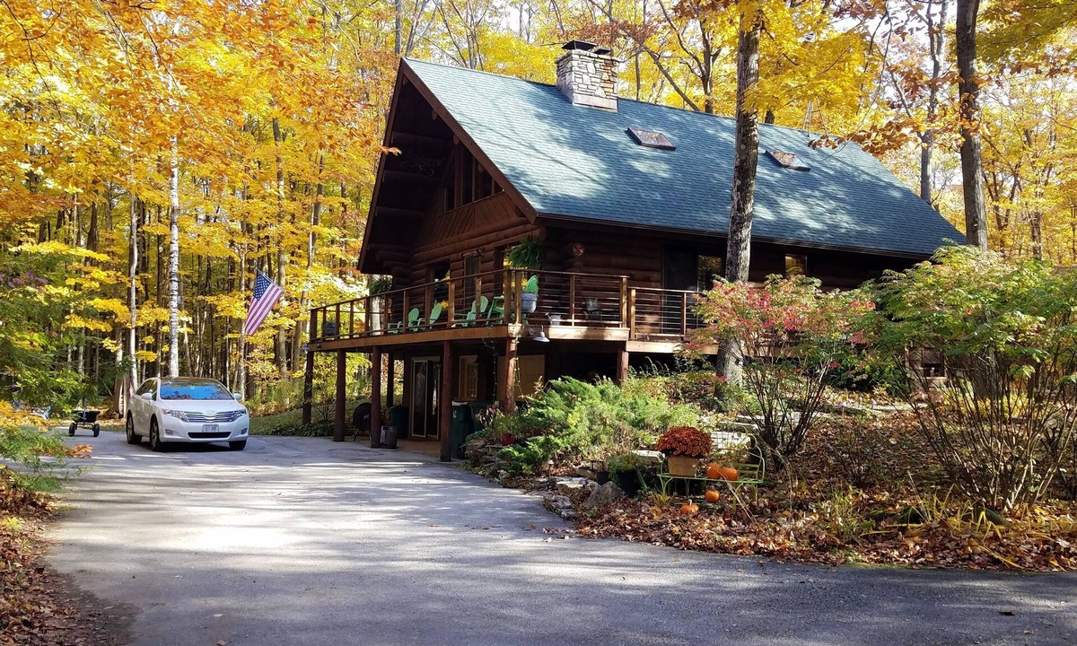 Egg Harbor House | Beautiful log home with wrap-around deck surrounded by trees.