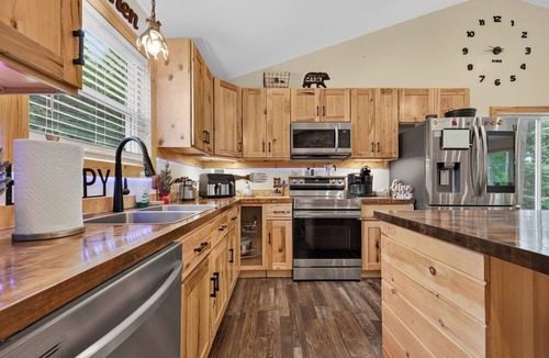 Galax House | A secluded, multi-level log cabin featuring a spacious wooden deck, open-concept living, a fully equipped modern kitchen, and comfortable sports-themed bunk rooms.